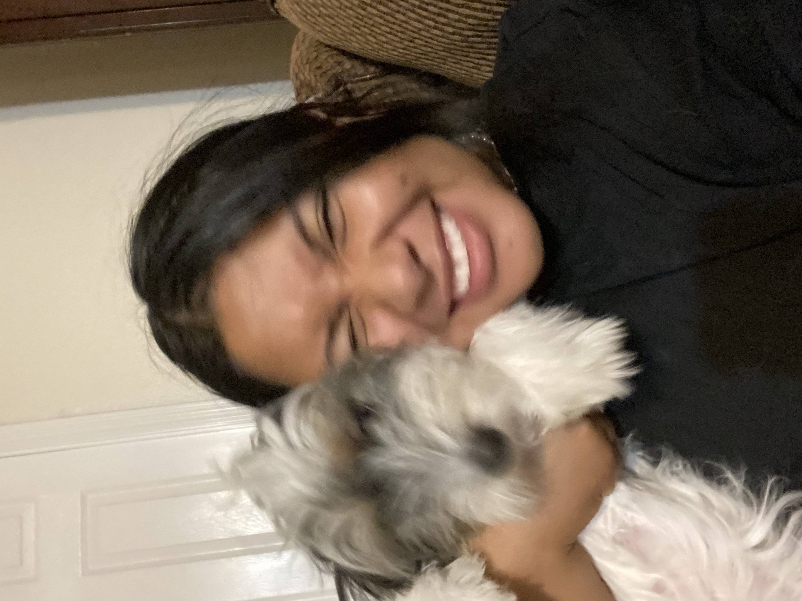 Headshot photo of Brandy Cervantes smiling with a cute white dog near her
                cheek.